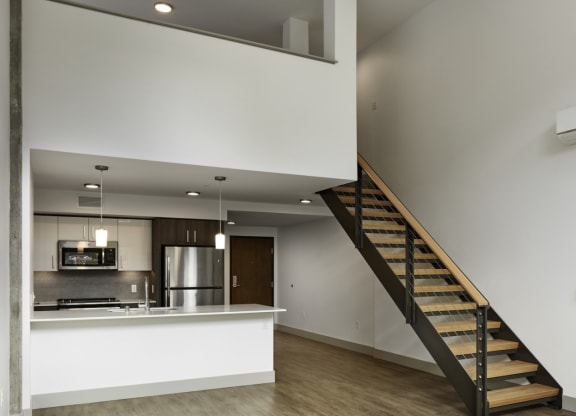 a living room with a staircase and a kitchen