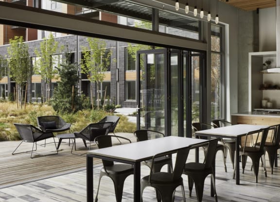 a dining area with tables and chairs and a kitchen with glass doors