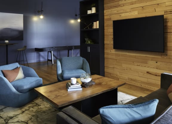 a living room with blue chairs and a table and a television