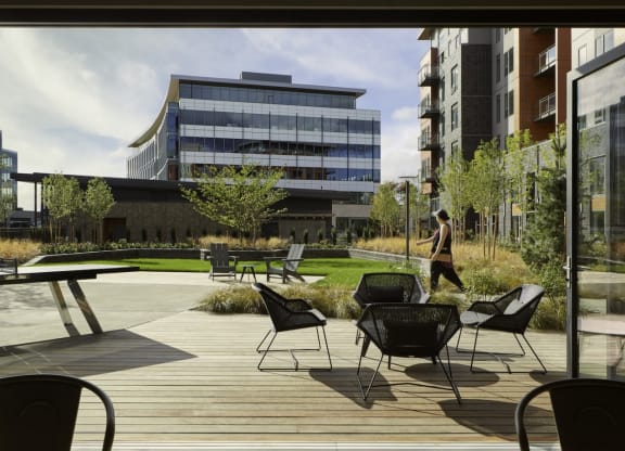 a patio area with chairs and tables and buildings in the background