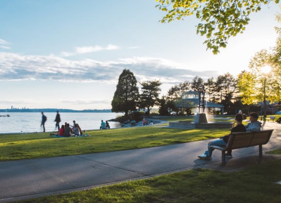 people sitting on a park bench near the water