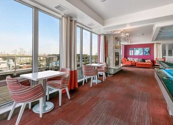 Spacious modern lounge here at Blue and Lime Apartments with large windows, red carpet, striped chairs, and white tables. Cozy seating area and fireplace create a warm, inviting atmosphere.