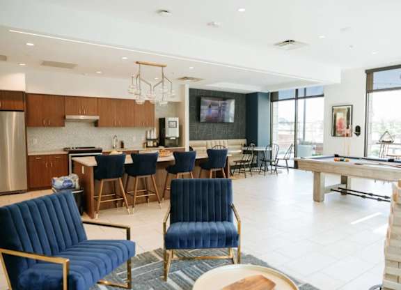 a living room with a bar and a kitchen with blue chairs