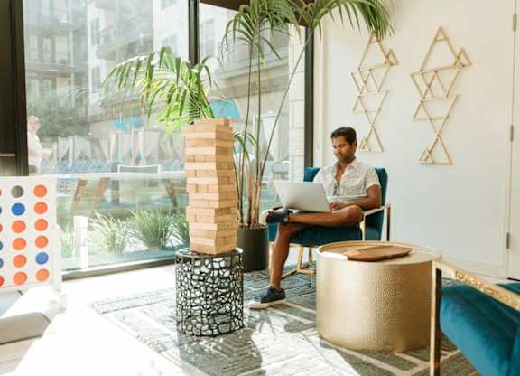 a man sitting in a chair using a laptop in a living room