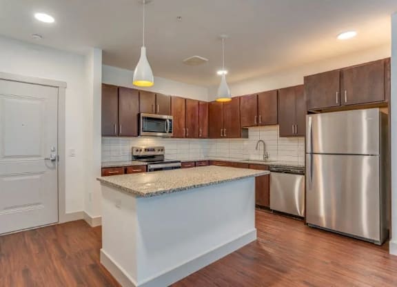 a kitchen with an island and a stainless steel refrigerator