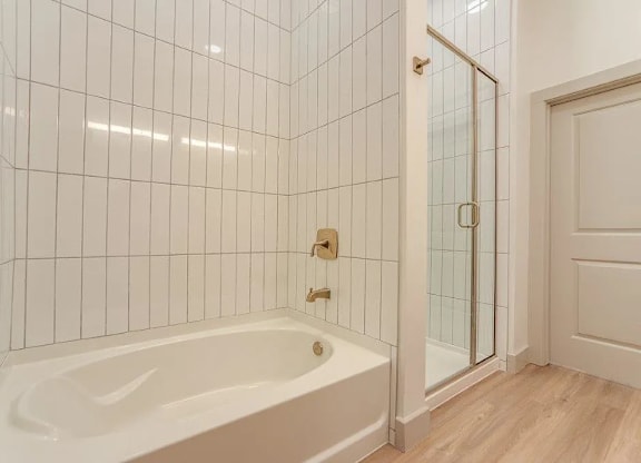a white tiled bathroom with a tub and a shower