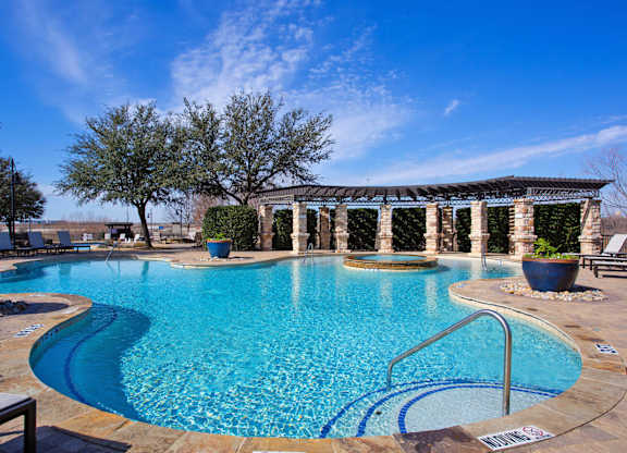 A swimming pool with a blue tinted water and a metal ladder.