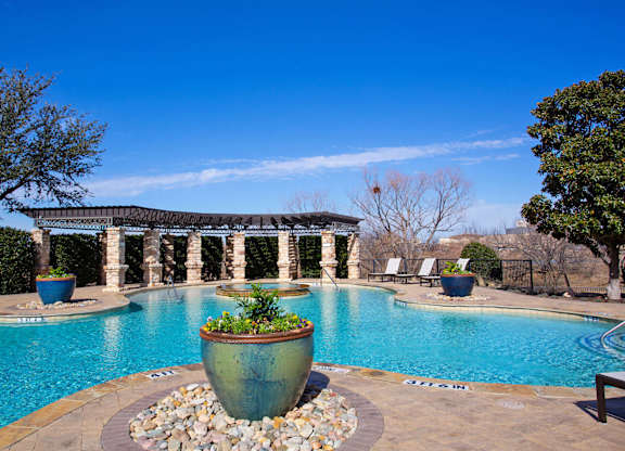 A large outdoor pool with a stone planter in the middle.