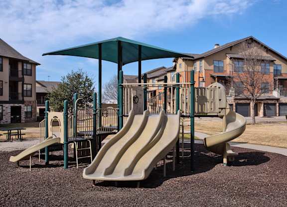 A playground with a green canopy and a slide.