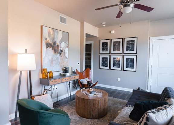 A living room with a green chair and a painting on the wall.