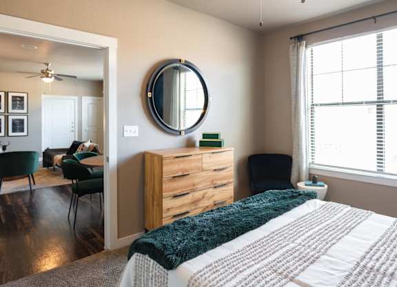 A bedroom with a bed, dresser, mirror, and chairs.