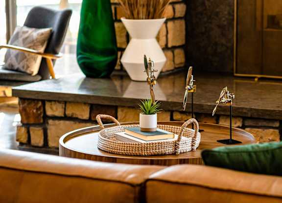 A living room with a brown leather couch and a woven coffee table.