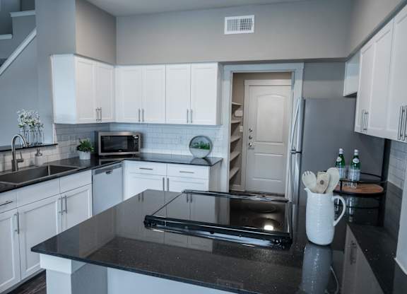 A modern kitchen with a black countertop and white cabinets.