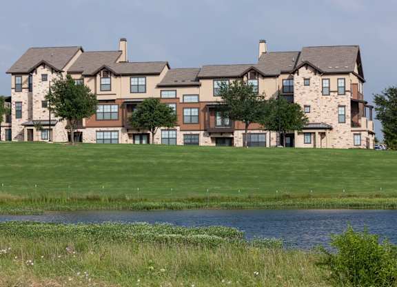 A large house with a brown roof and a green lawn in front.