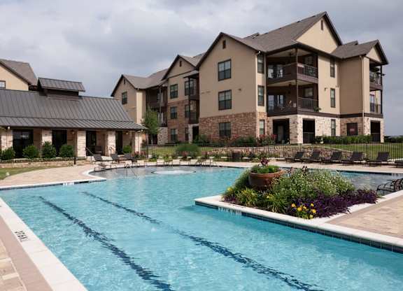 A large swimming pool in front of a multi-story apartment building.