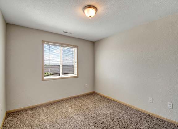A room with a window and carpeted floor.