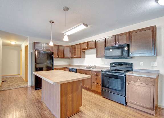 A kitchen with a black fridge, black stove, and black microwave.