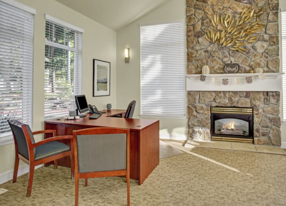 a room with a fireplace and a desk and chairs
