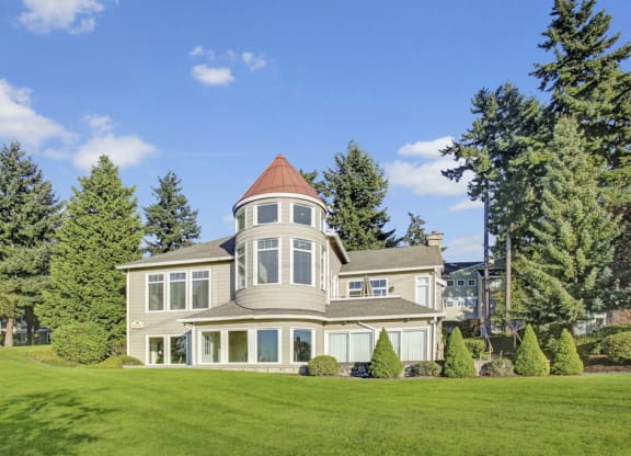 a large house with a tower on top of a grassy hill