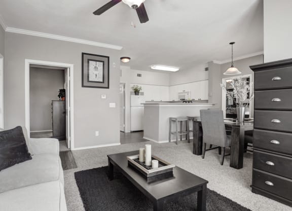 a black and white photo of a living room with a kitchen in the background
