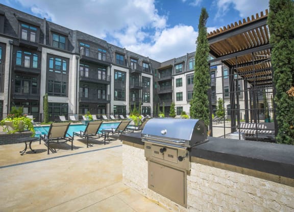 a patio with a grill and a pool in front of an apartment building