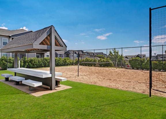 a picnic area with a picnic table and benches next to a volleyball court