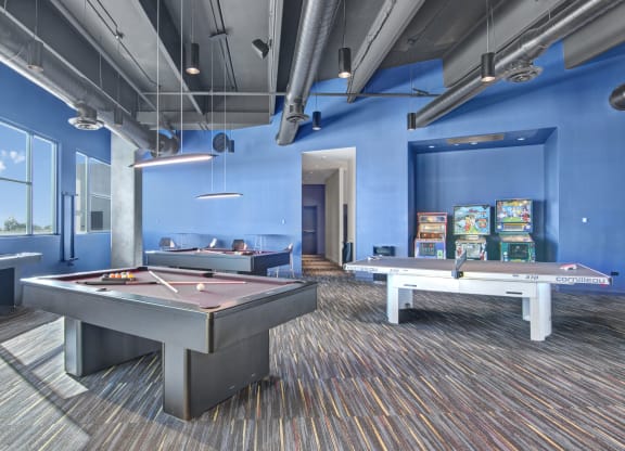 a games room with two pool tables and arcade games