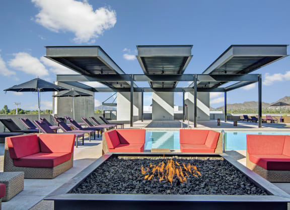 a lounge area with couches and chairs around a fire pit