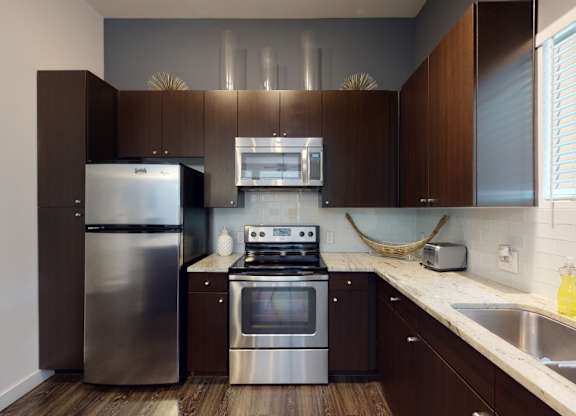 A modern kitchen with dark wood cabinets and stainless steel appliances.