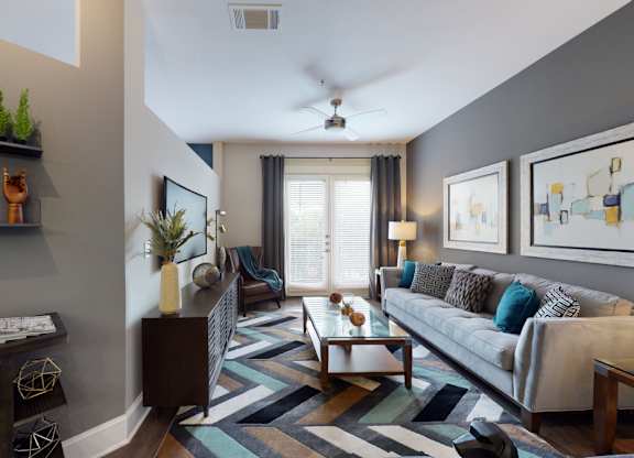 A living room with a grey couch and a striped rug.
