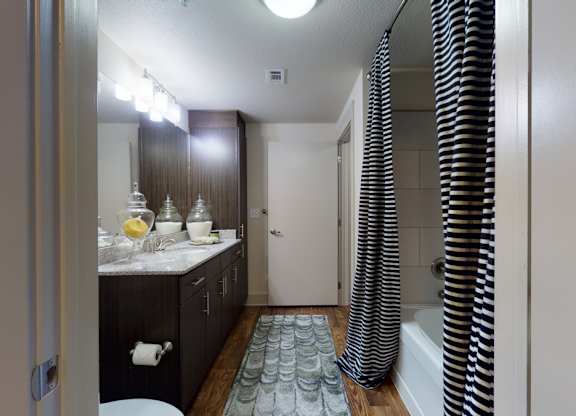 A bathroom with a sink, mirror, and shower.