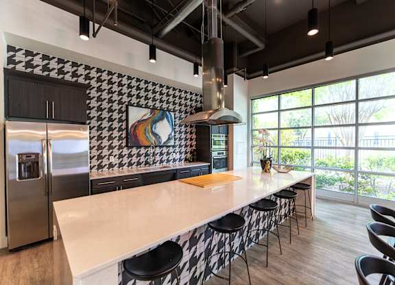 A modern kitchen with a long counter and bar stools.