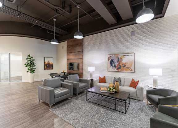A modern living room with a grey sofa, armchairs, and a coffee table.