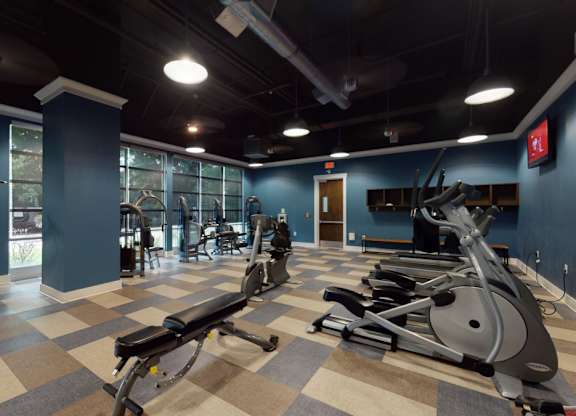 A gym with a variety of exercise equipment including treadmills, stationary bikes, and weight machines.