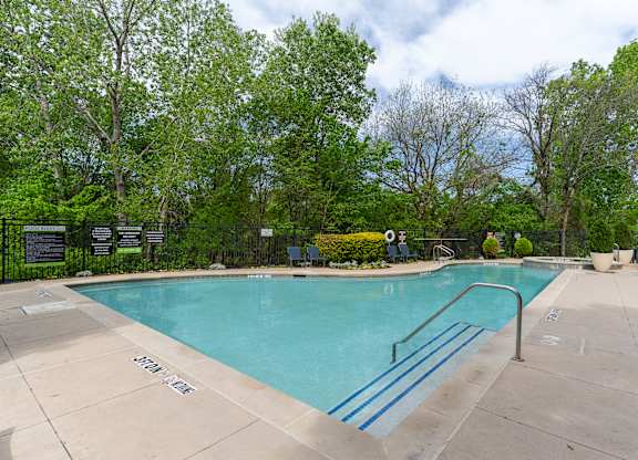 A small pool surrounded by trees and a fence.