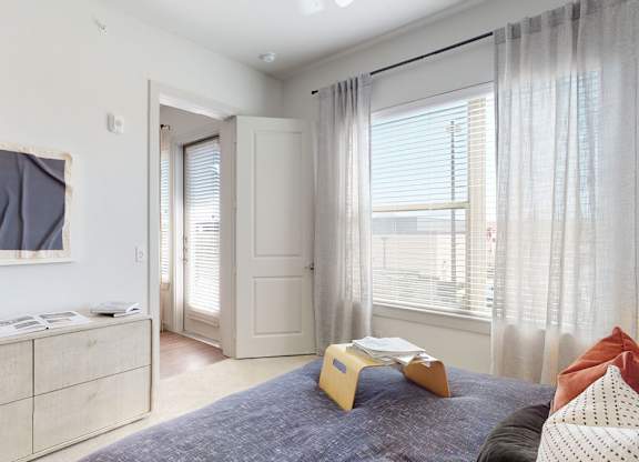A bedroom with a bed, dresser, and window.