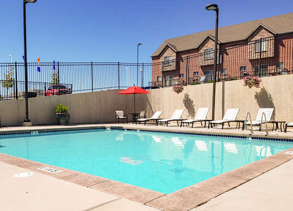A pool with chairs and umbrellas in front of a building.