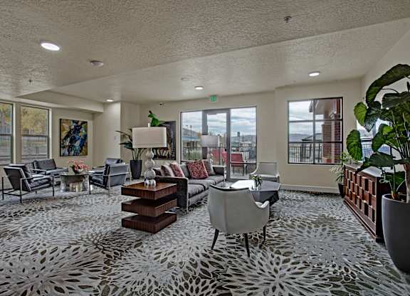 A spacious living room with a grey patterned carpet and furniture.