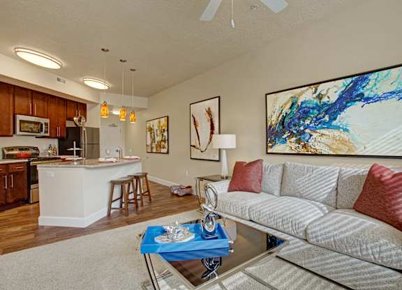 A living room with a grey couch and a painting on the wall.