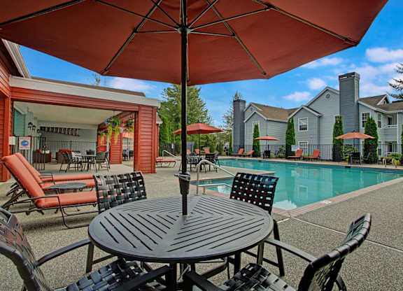 A patio with a table and chairs under an umbrella.