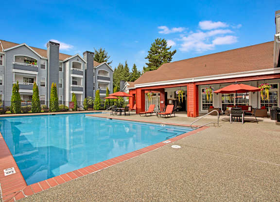 A large swimming pool in front of a building with a red awning.