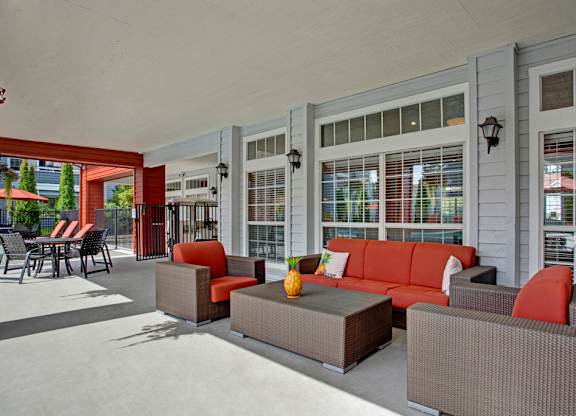 A patio with a couch, chairs, and a table with a pineapple on it.