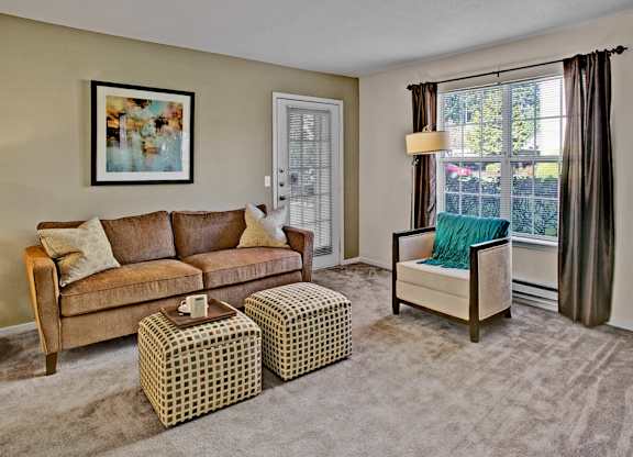 A living room with a brown couch, a green chair, and a painting on the wall.