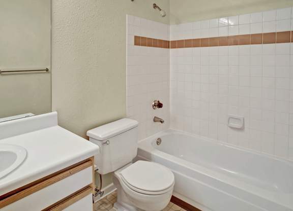 A white toilet sits next to a white bathtub in a bathroom.