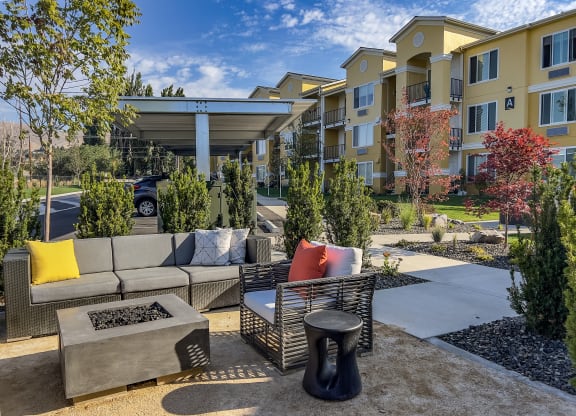 a patio with couches and a coffee table in front of an apartment building
