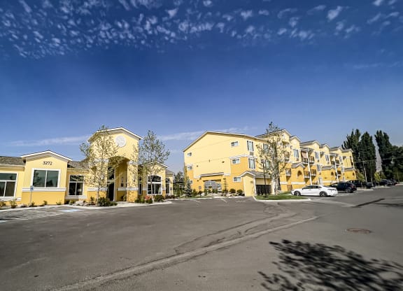 a row of apartment buildings with a parking lot in front of them