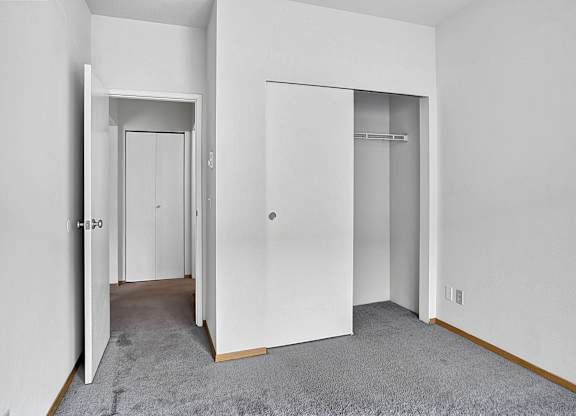 A white hallway with two doors and a carpeted floor.