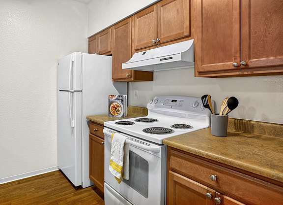 A white refrigerator sits next to a stove in a kitchen.