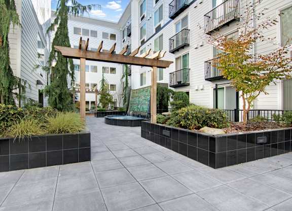 A courtyard with a wooden arch and a black tile border.
