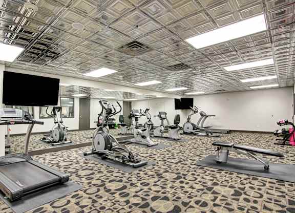 A gym with treadmills, exercise bikes and a television.